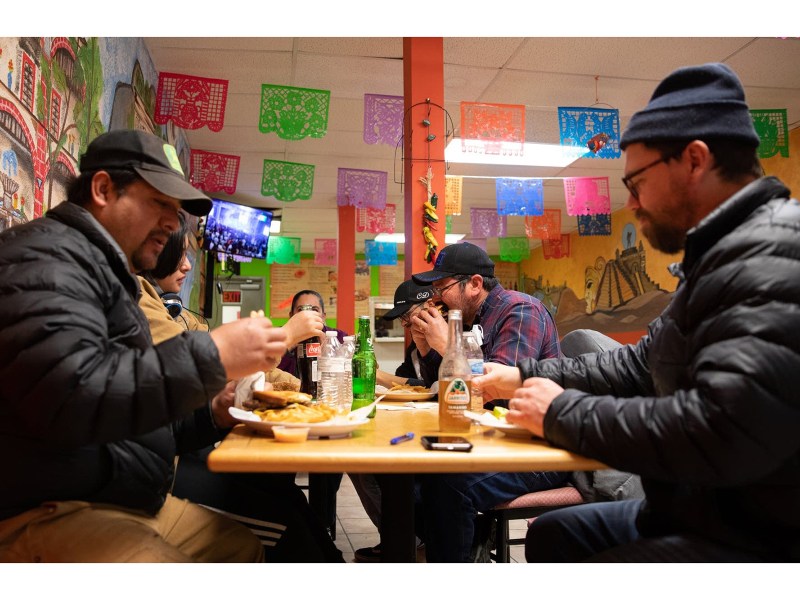 Rodrigo Cala (left) and Aaron Blythe (right) eat a late lunch with Javier Garcia (center) and his family after meeting about their cooperatively owned and run farm, Agua Gorda at Mi Pueblito, Jose Garcia's market and restaurant in Long Prairie, Minn. on February 27, 2021.